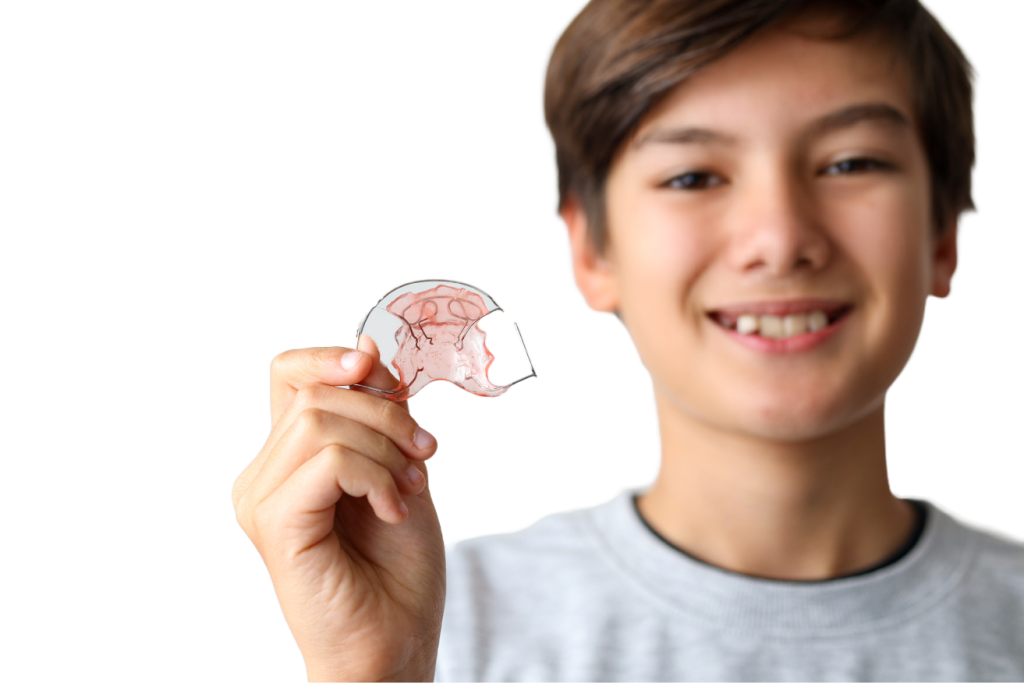 Garçon souriant tenant son appareil orthodontique