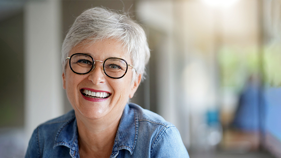Femme senior souriante avec des prothèses dentaires, illustrant le confort et l’esthétique offerts par les solutions modernes.