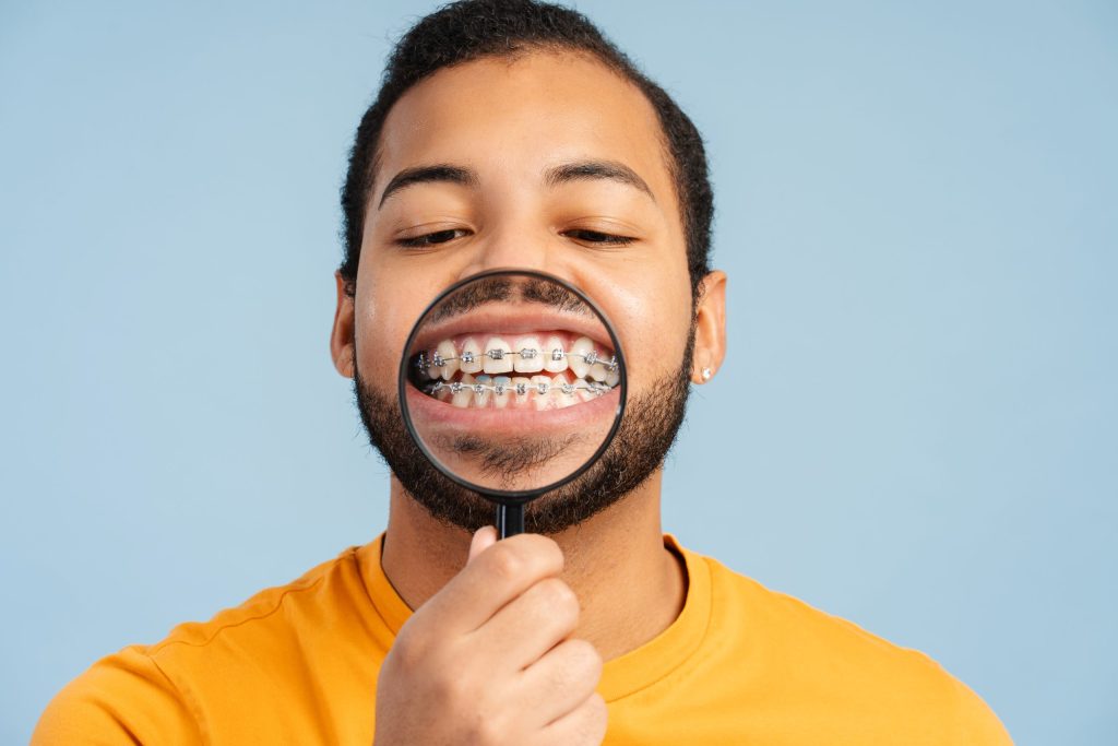 Homme montrant ses bagues orthodontiques à la loupe